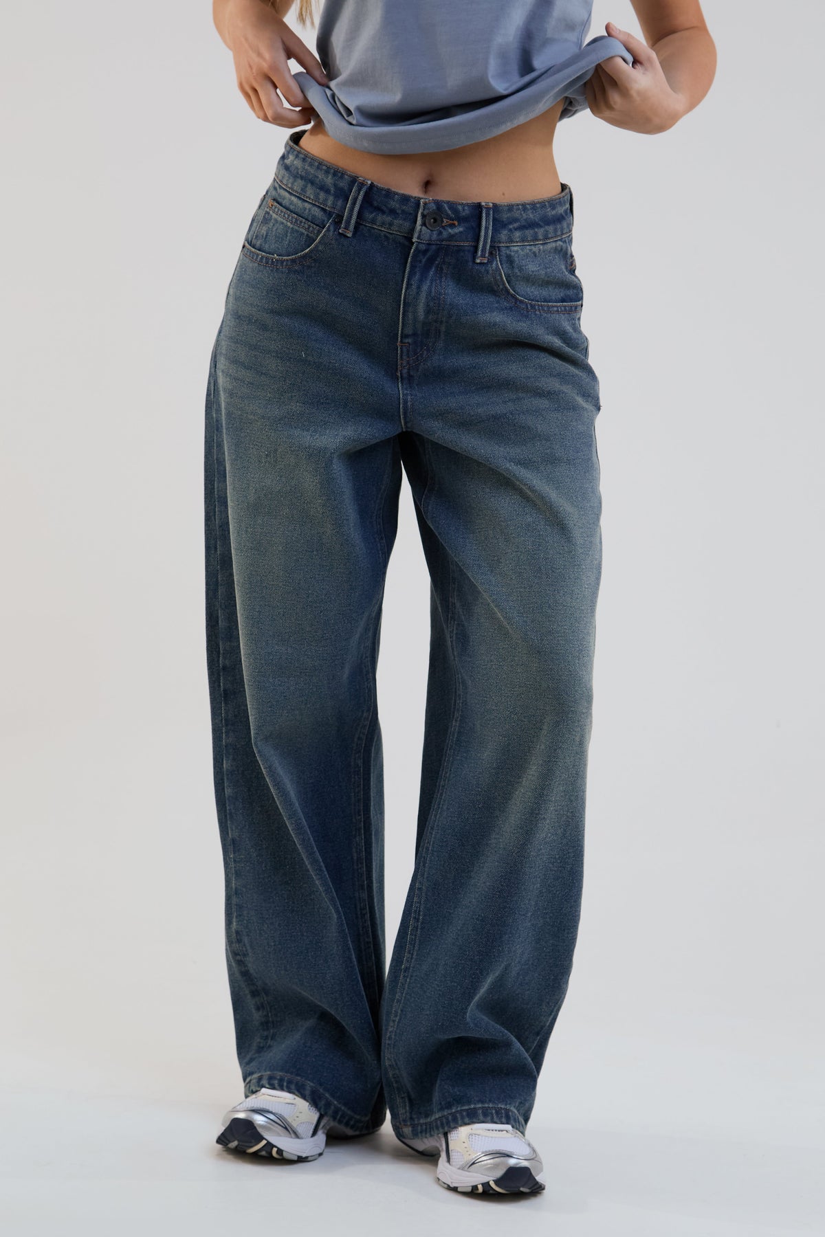 Person wearing blue wide-leg jeans on a plain background