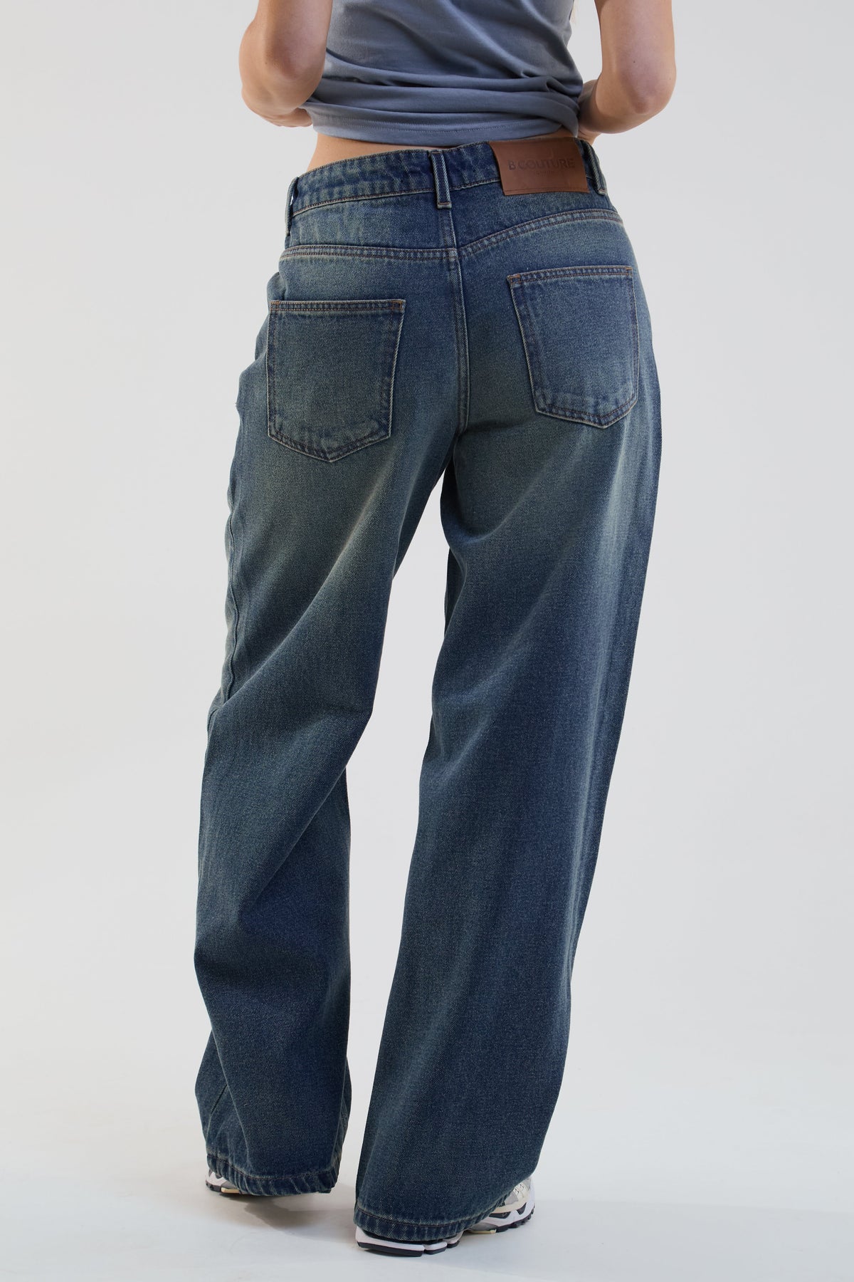 Person wearing blue jeans on a plain background