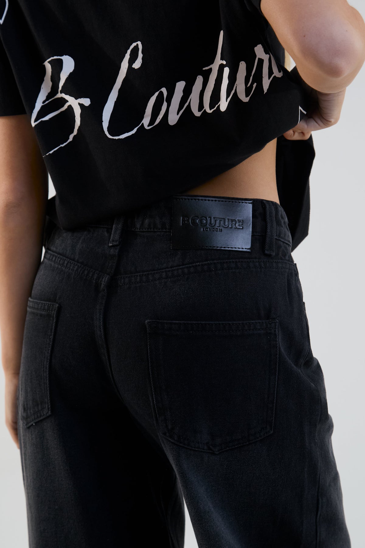 Person wearing a black 'B Couture' crop top and black pants on a plain background