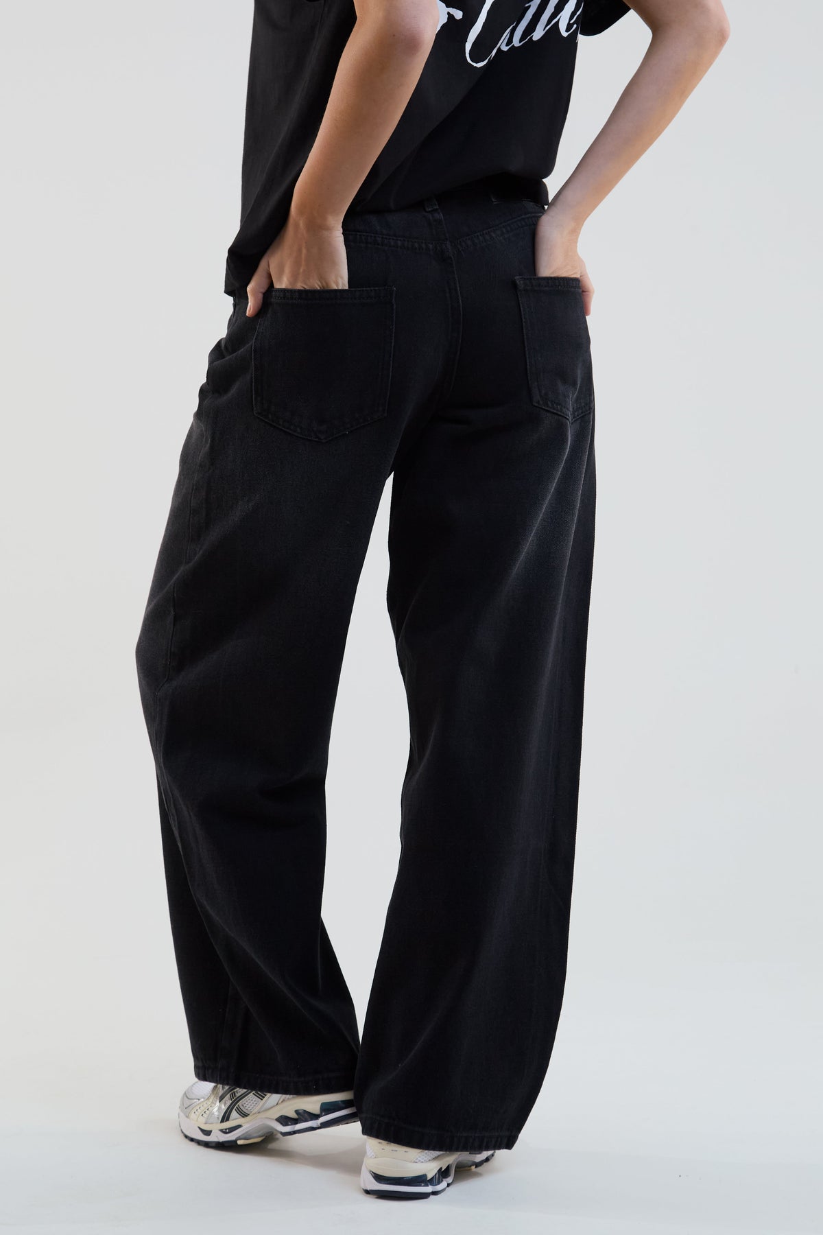 Person wearing black wide-leg pants on a plain background