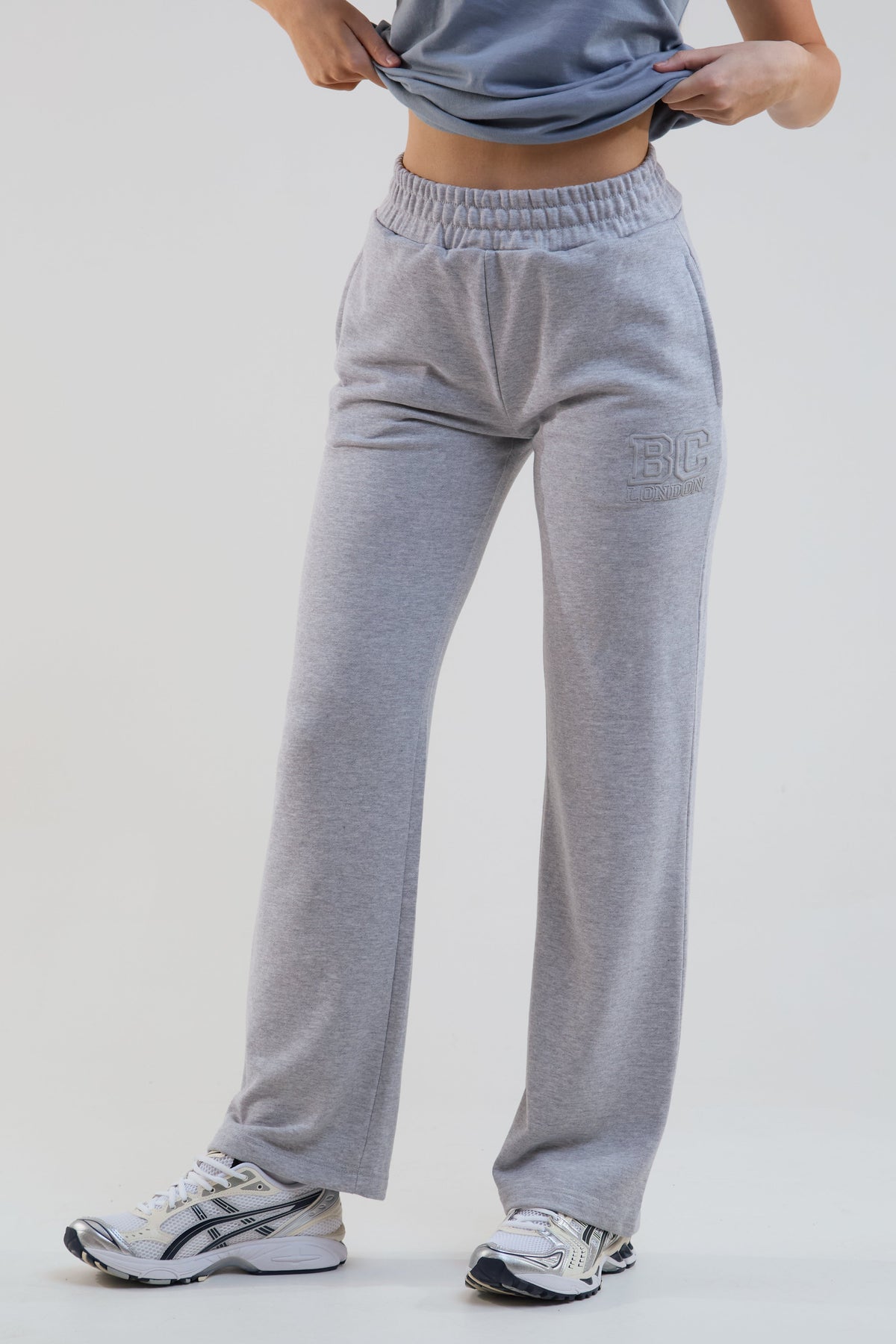 Person wearing gray sweatpants with a brand logo on a white background