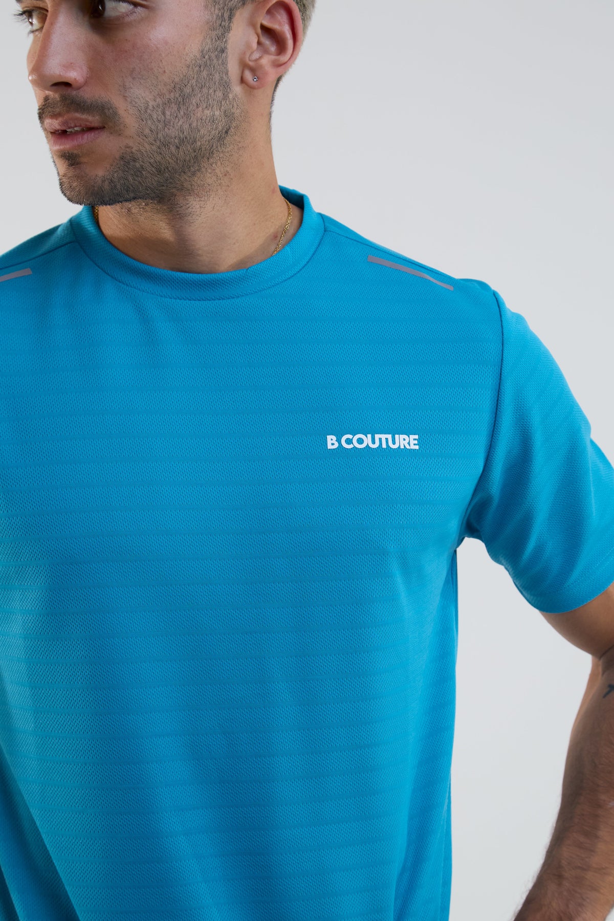 Man wearing a blue t-shirt with 'B Couture' logo on a white background