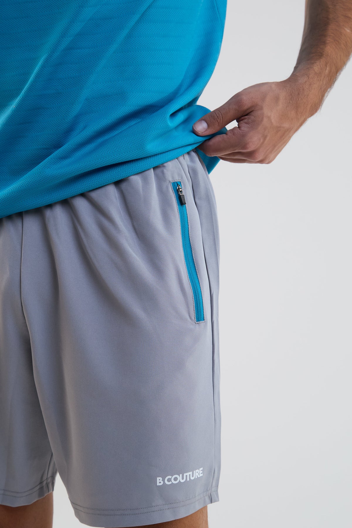 Gray shorts with a blue zipper and 'B Couture' branding on a white background