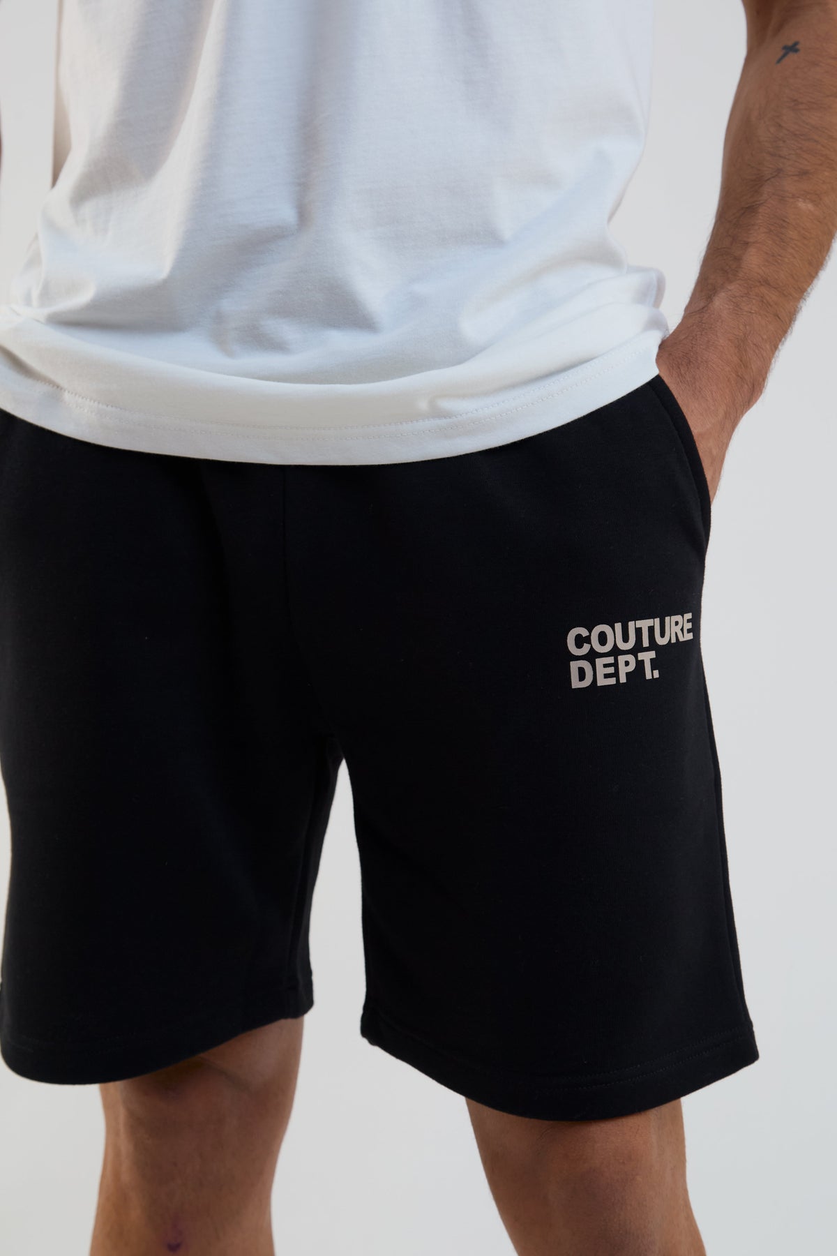 Person wearing black shorts with 'Couture Dept.' text on a plain background