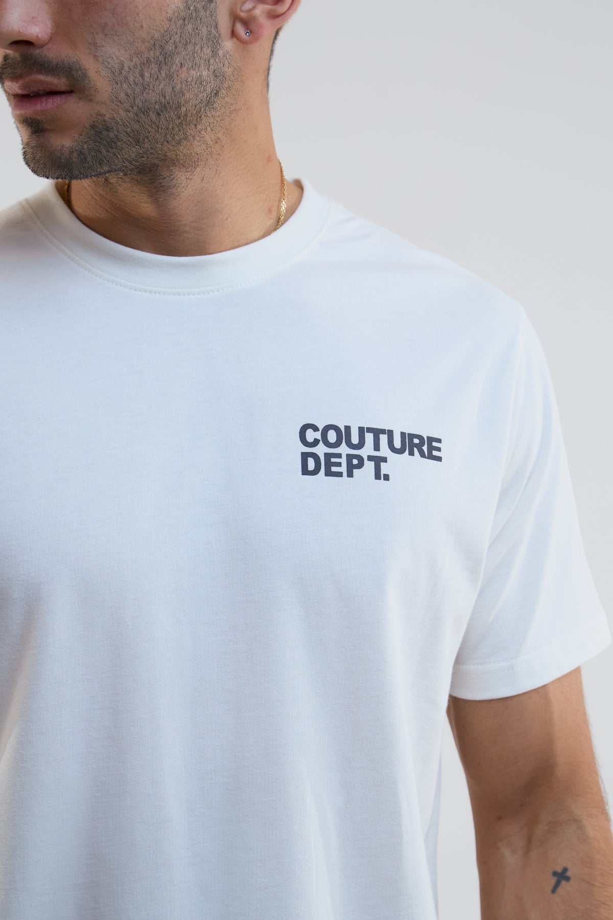 White t-shirt with 'COUTURE DEPT.' text worn by a person on a plain background