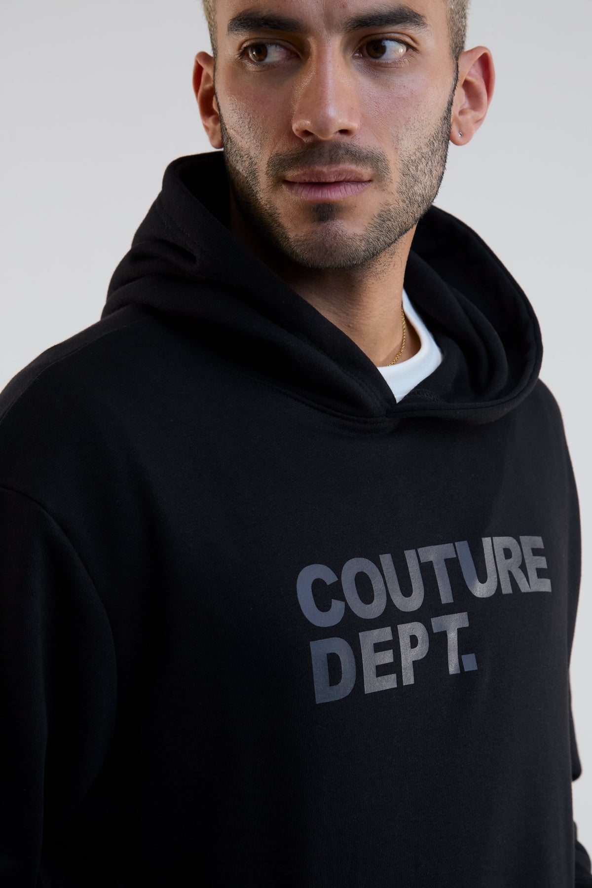 Man wearing a black hoodie with 'Couture Dept.' text on a plain background