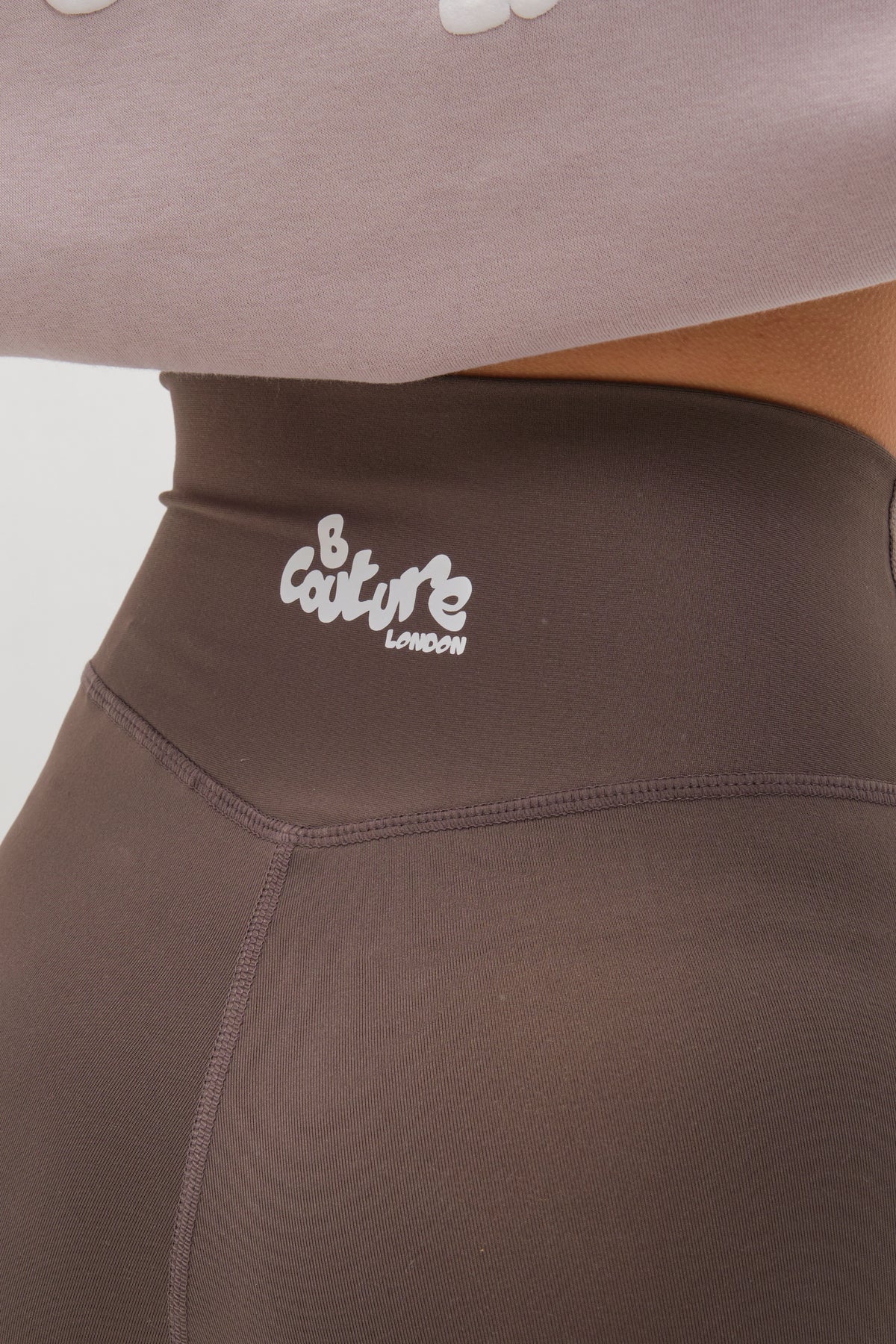 Close-up of the Hatherley Half-Zip Sweatshirt & Leggings Set in Stone, featuring high-waisted leggings with a white B Couture London logo and a cosy sweatshirt peeking out for a stylish, comfortable look.
